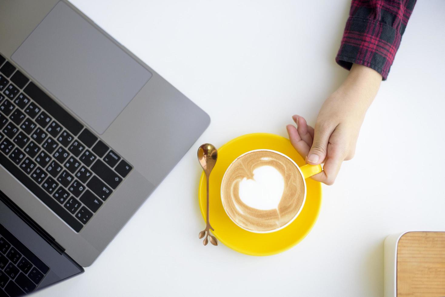 arte del latte caldo in tazza gialla sulla scrivania foto