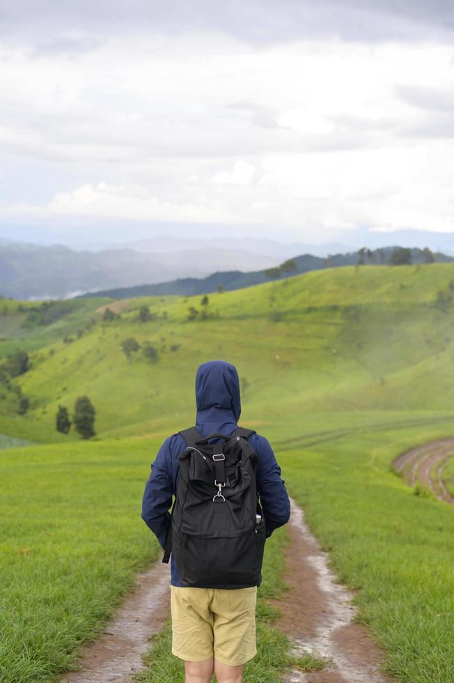 uomo in viaggio che si diverte e si rilassa su una splendida vista sulle montagne verdi nella stagione delle piogge, clima tropicale. foto