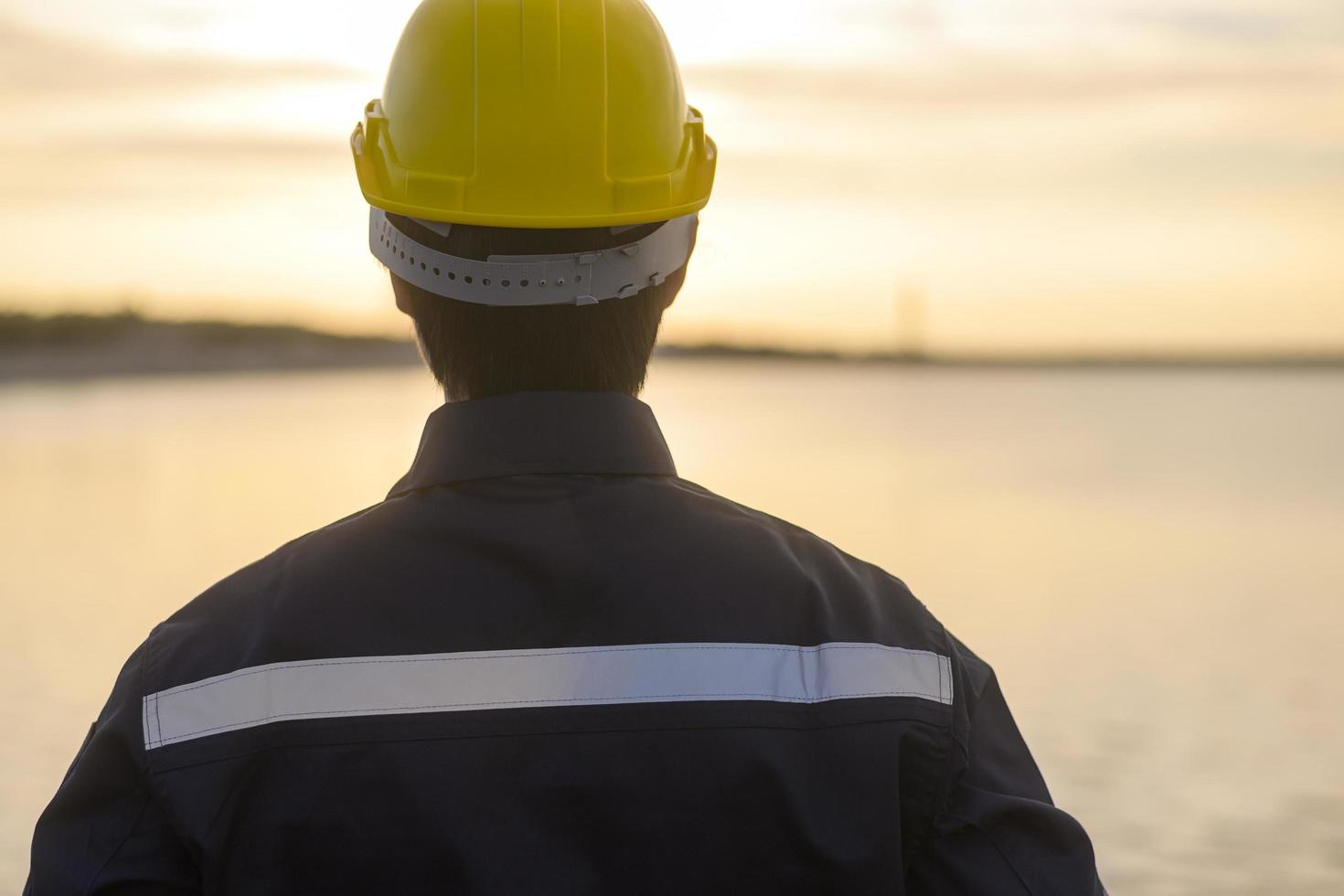 un ingegnere maschio che indossa un casco protettivo al tramonto. foto