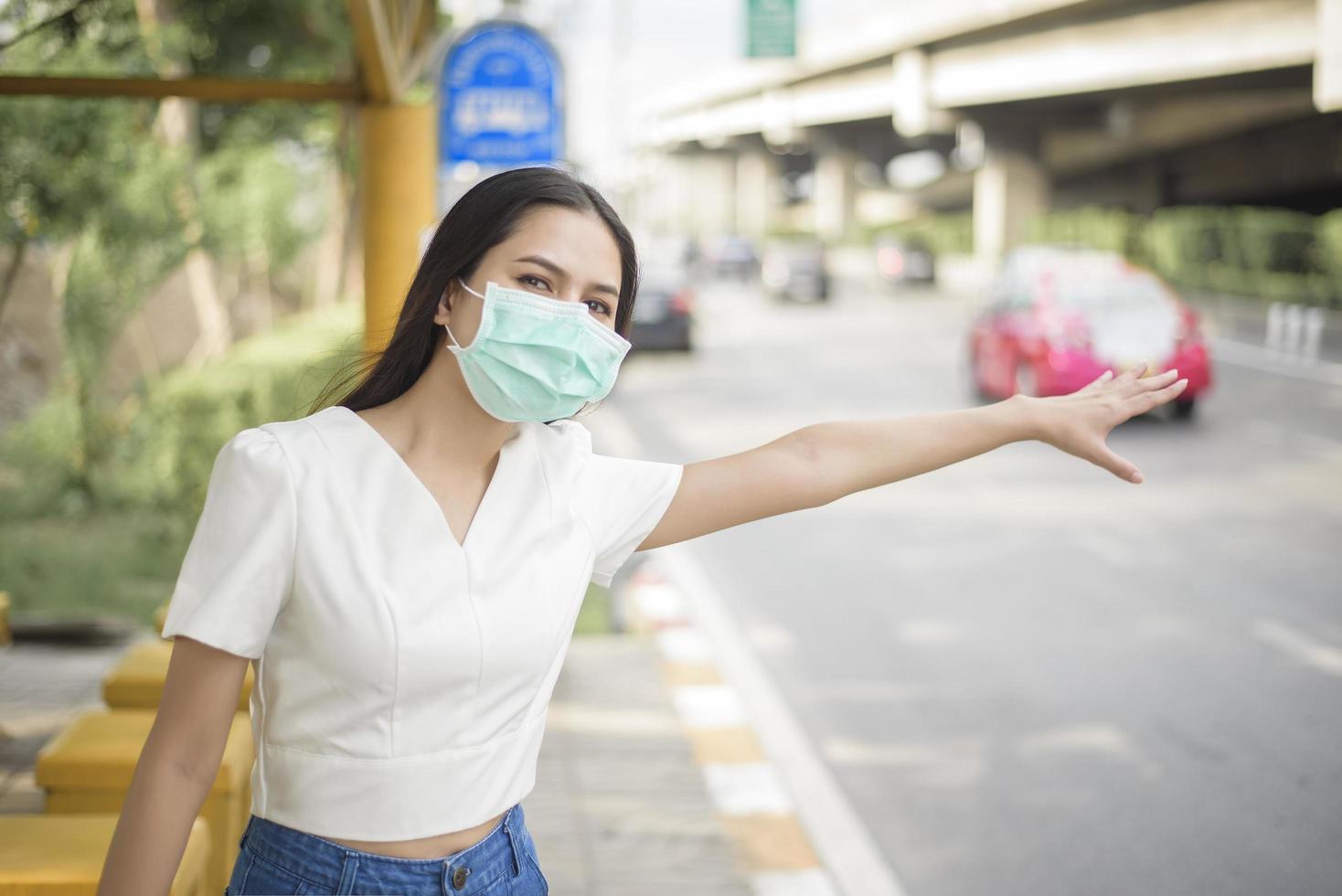 bella donna indossa una maschera alla fermata dell'autobus foto