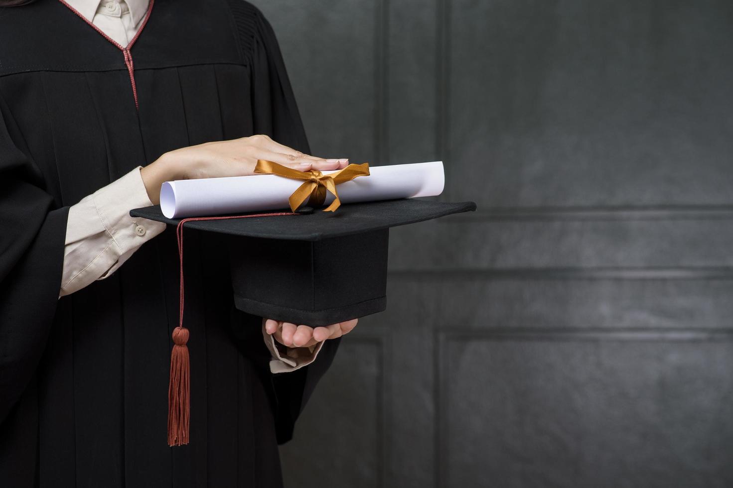 primo piano la donna di laurea tiene in mano berretto e certificato foto