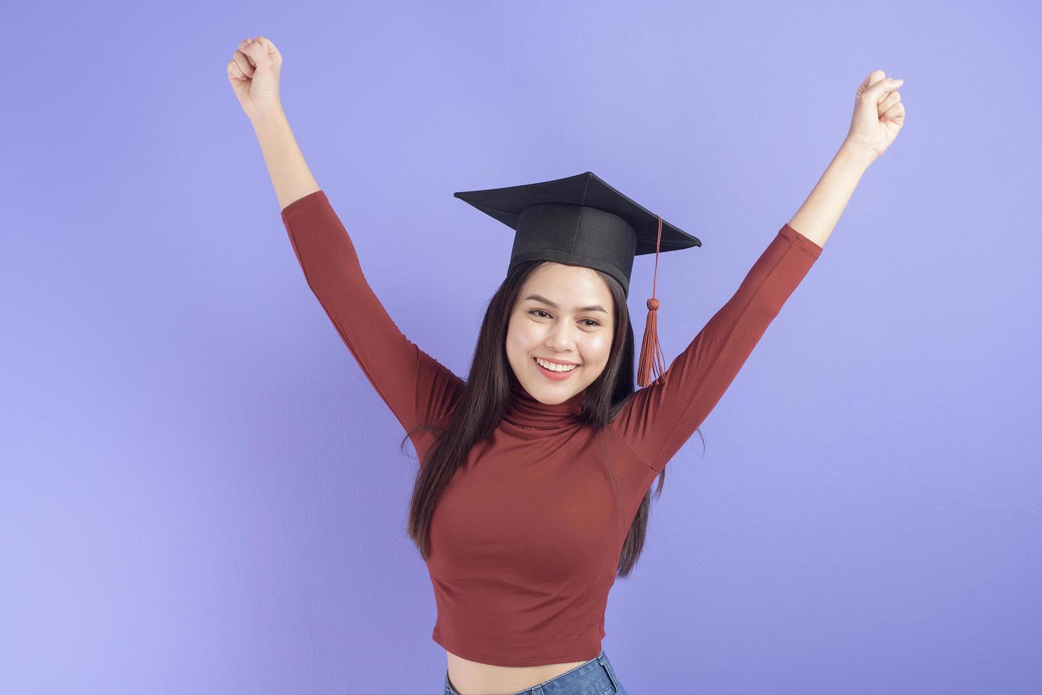 ritratto di giovane studentessa universitaria con cappuccio di laurea su sfondo viola foto