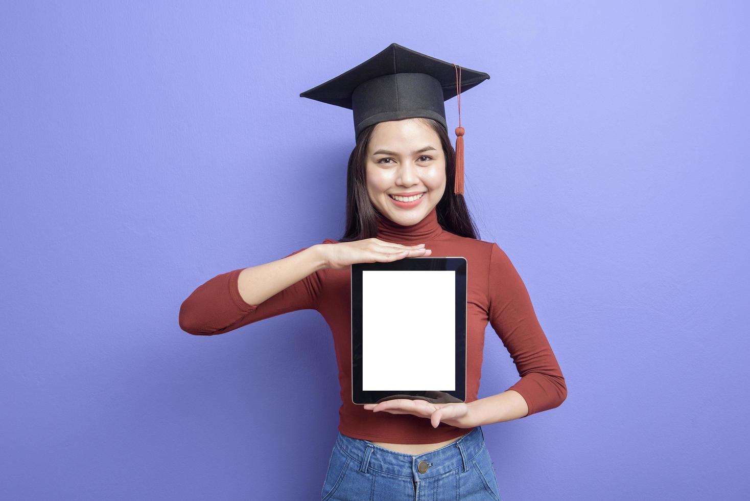 ritratto di giovane studentessa universitaria con cappuccio di laurea su sfondo viola foto