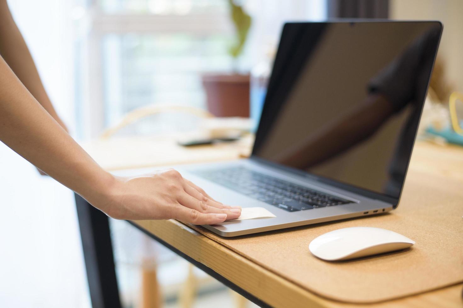 la donna sta pulendo il laptop con uno spray alcolico foto