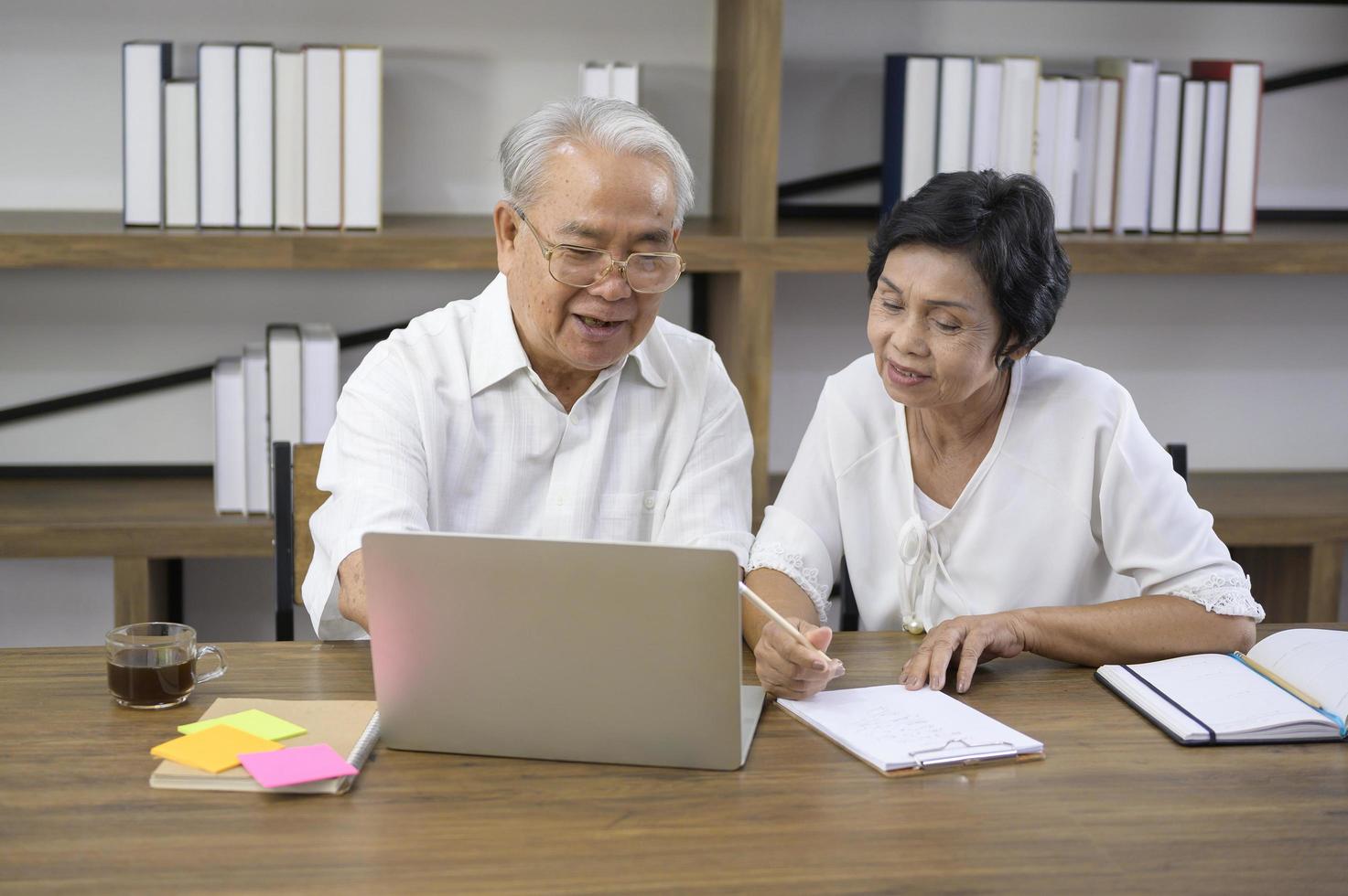 una felice coppia asiatica senior sta trascorrendo del tempo a navigare in Internet e parlare con la famiglia in webcam, concetto di pensionamento. foto