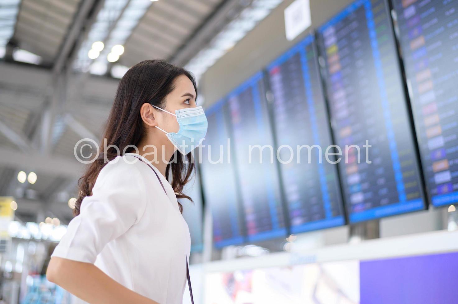 una donna viaggiatrice indossa una maschera protettiva nell'aeroporto internazionale, viaggia sotto la pandemia covid-19, viaggi di sicurezza, protocollo di allontanamento sociale, nuovo concetto di viaggio normale foto