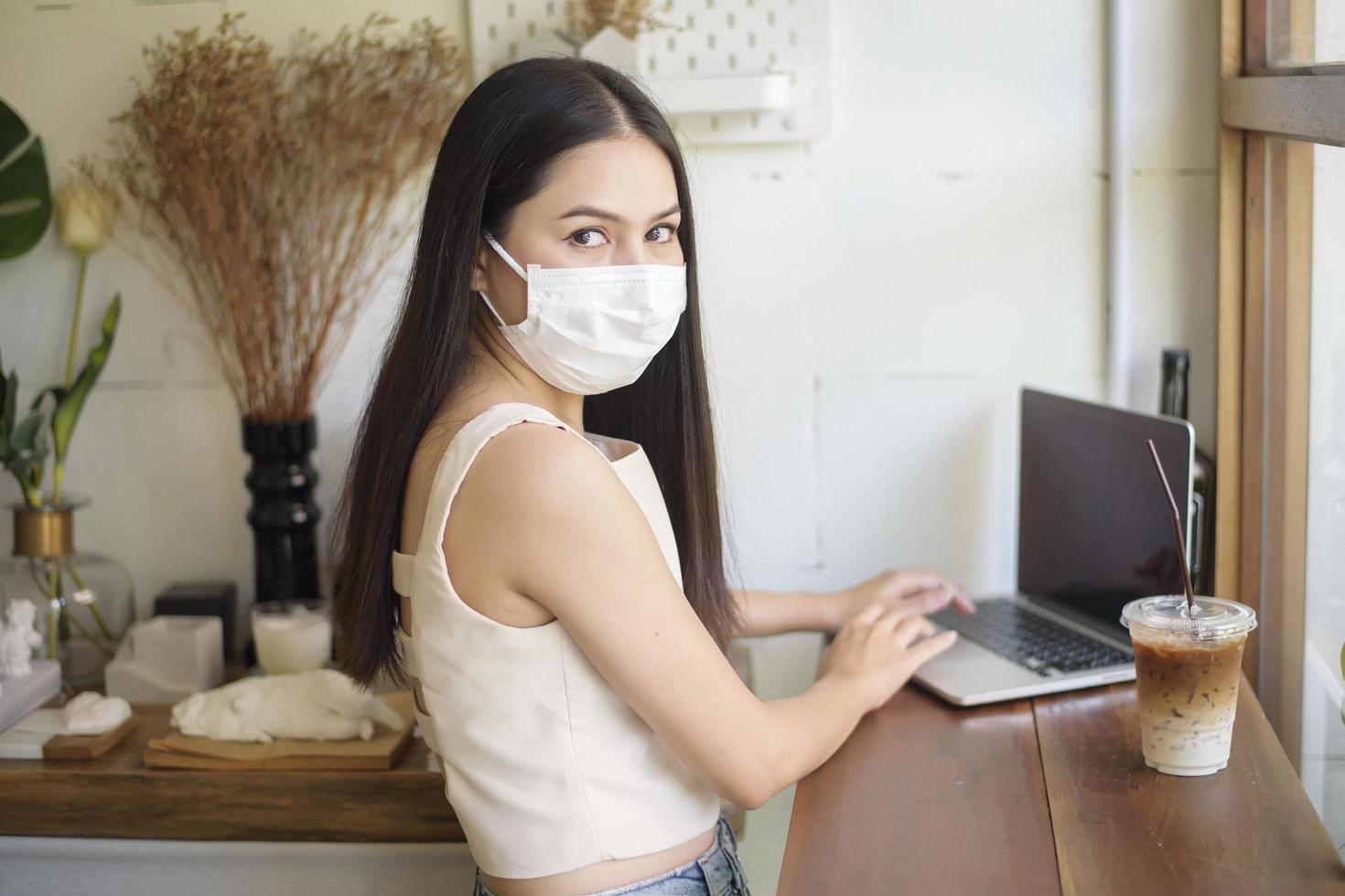 bella giovane donna con maschera facciale è seduta in una caffetteria foto