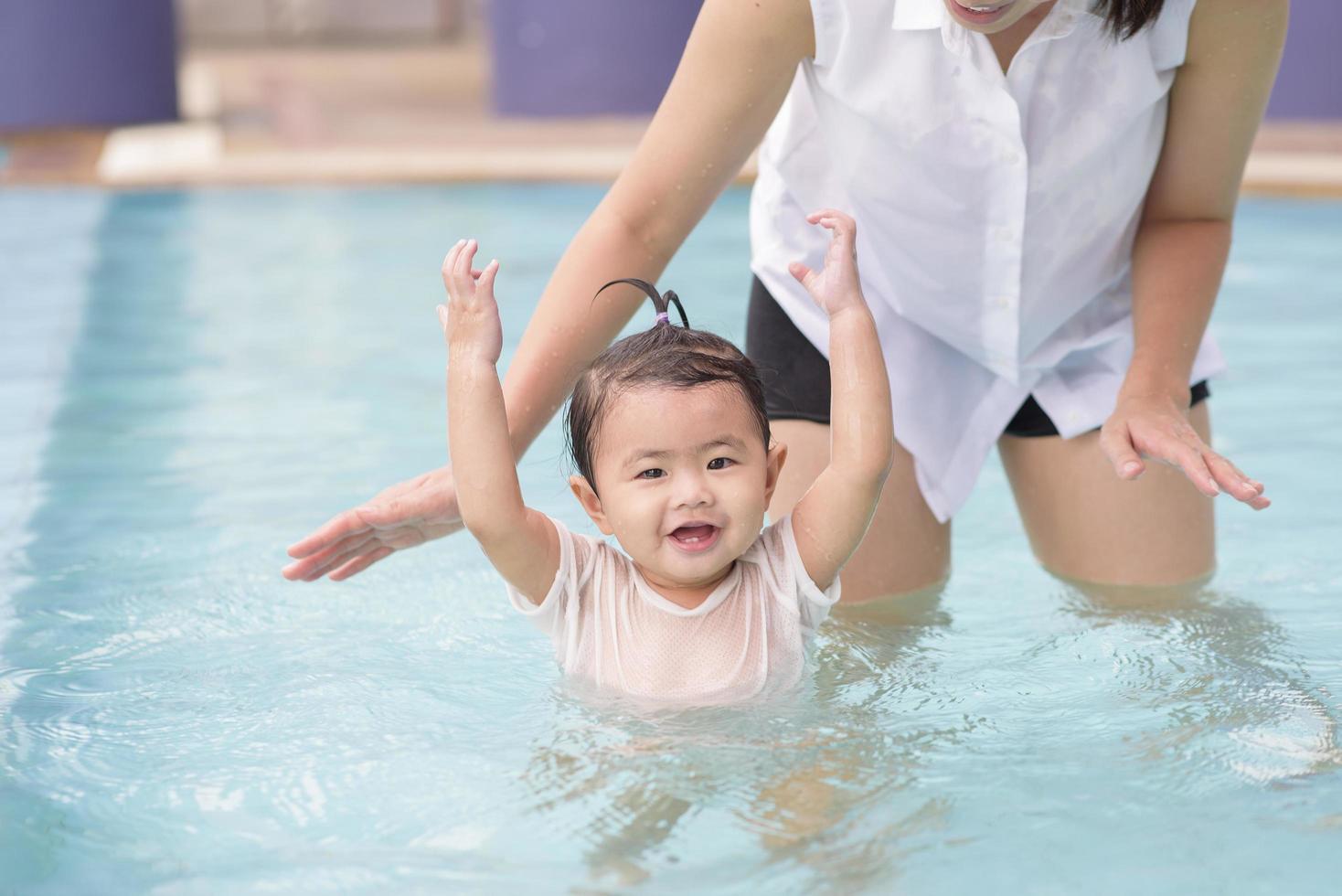 una felice madre e figlia asiatiche si divertono a nuotare in piscina, lo stile di vita, la genitorialità, il concetto di famiglia foto