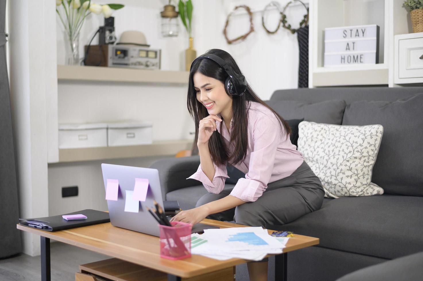 una giovane e bella donna che indossa l'auricolare sta effettuando una videoconferenza tramite computer a casa, concetto di tecnologia aziendale. foto