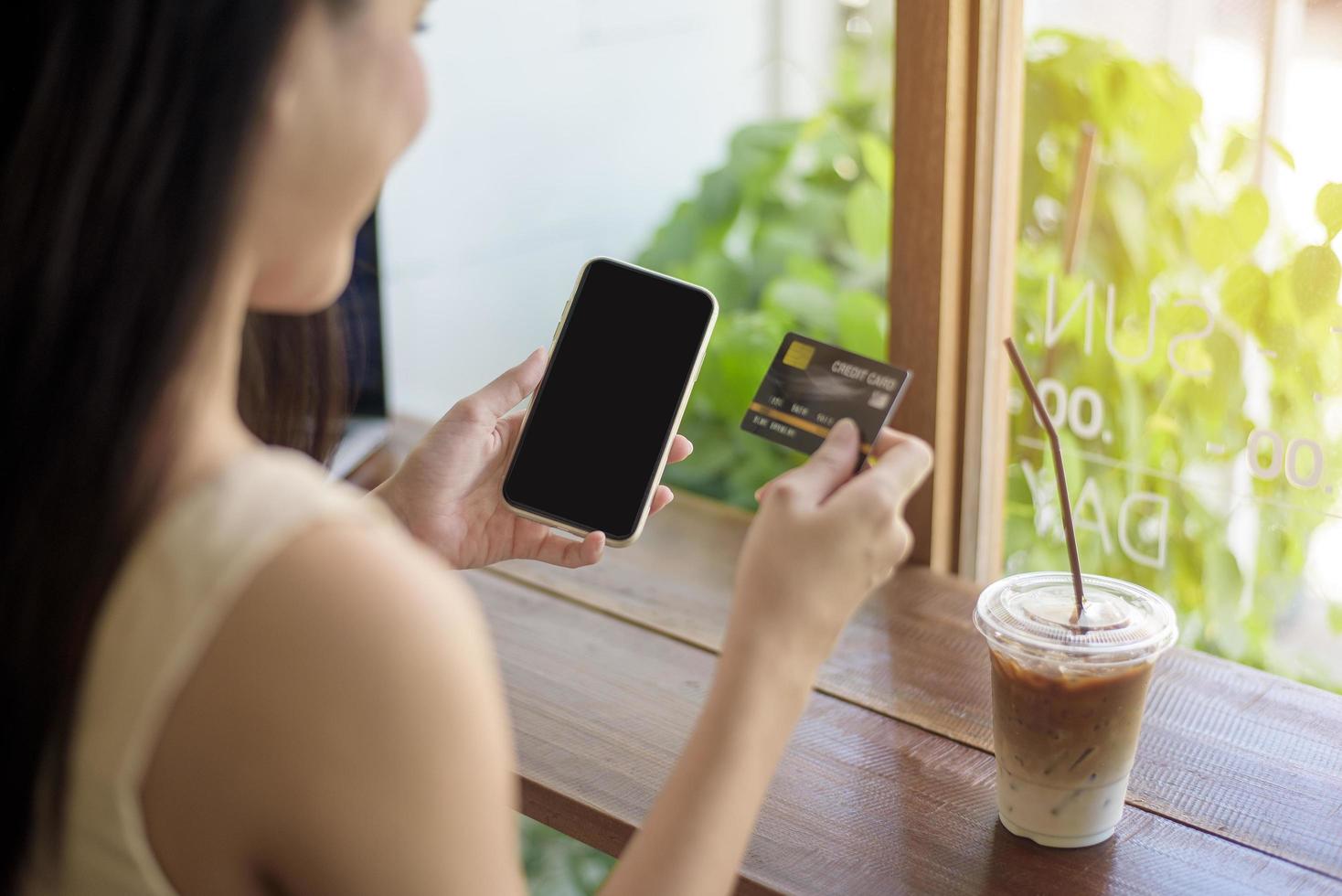 primo piano la mano della donna tiene la carta di credito e il cellulare, concetto di shopping online foto