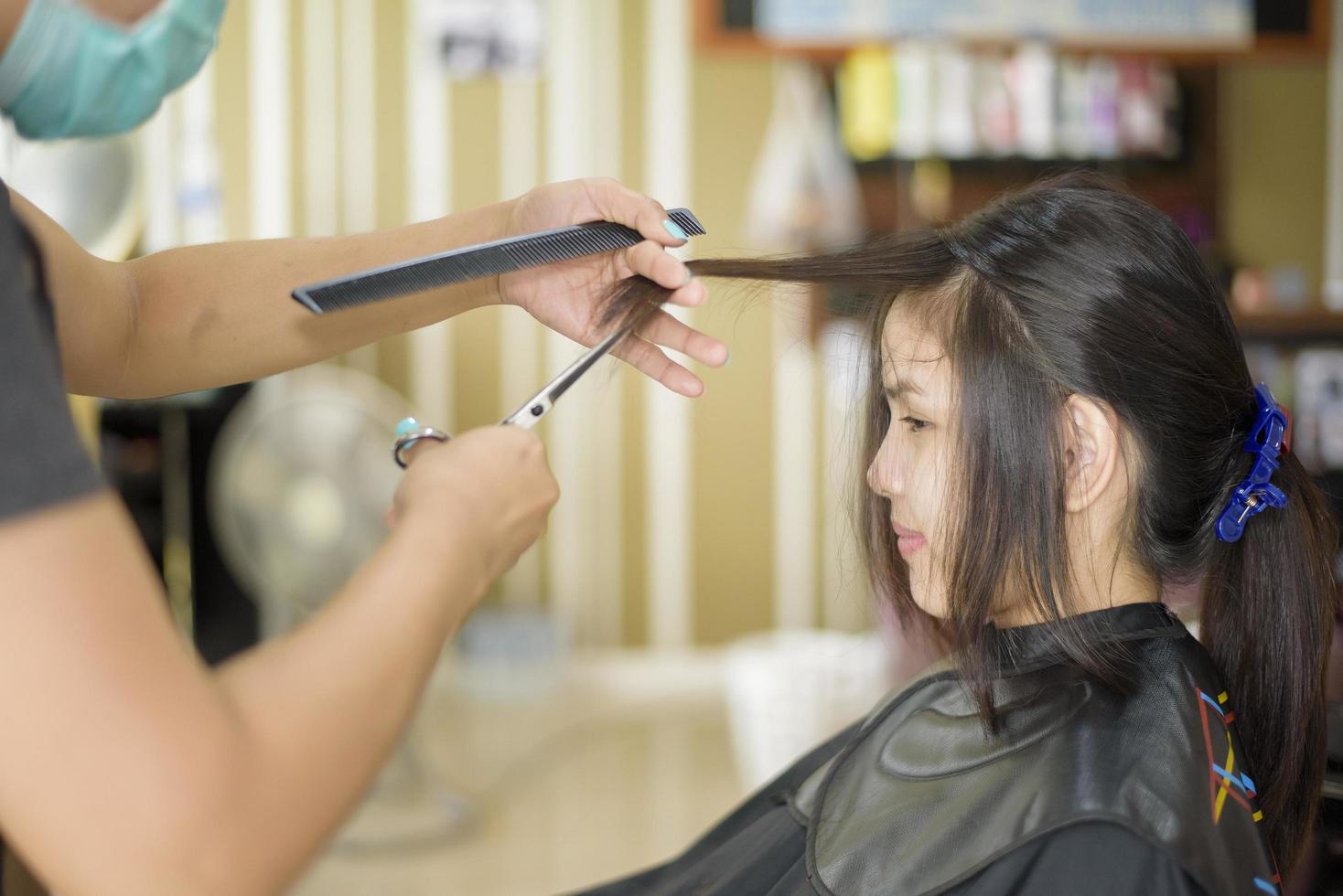 una giovane donna sta ottenendo un taglio di capelli in un parrucchiere, concetto di sicurezza del salone foto