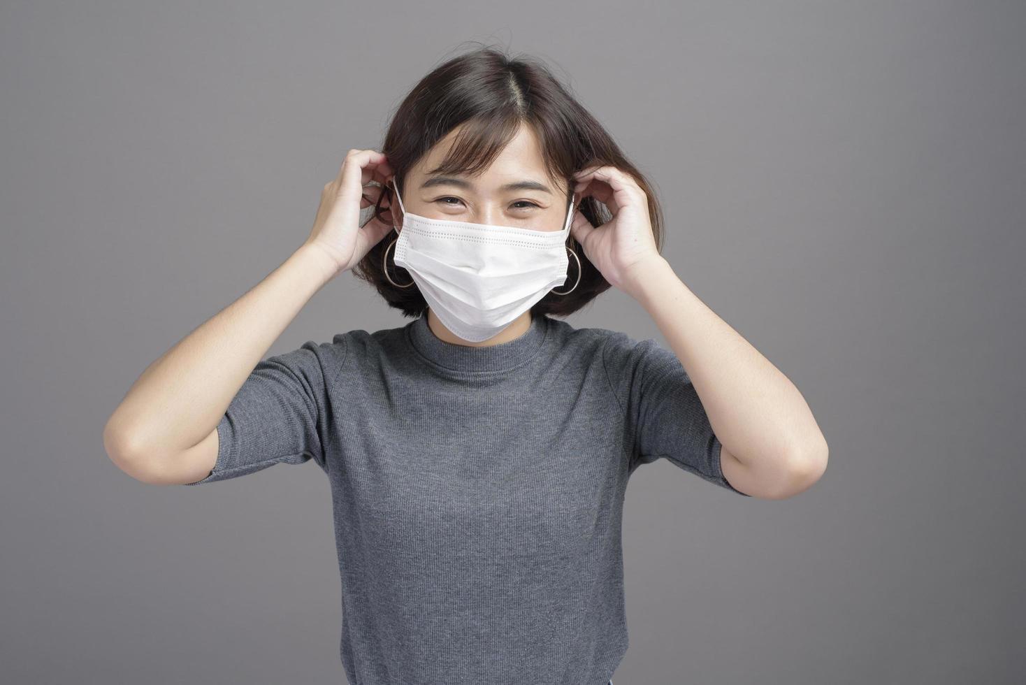 ritratto di giovane bella donna asiatica che indossa una maschera chirurgica su sfondo di studio covid19 pandemia e inquinamento atmosferico foto