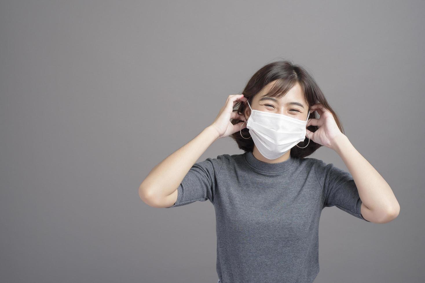 ritratto di giovane bella donna asiatica che indossa una maschera chirurgica su sfondo di studio covid19 pandemia e inquinamento atmosferico foto