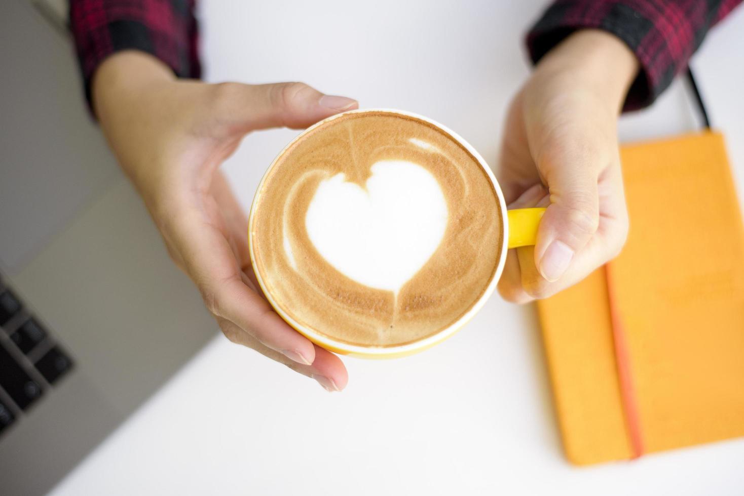 arte del latte caldo in tazza gialla sulla scrivania foto