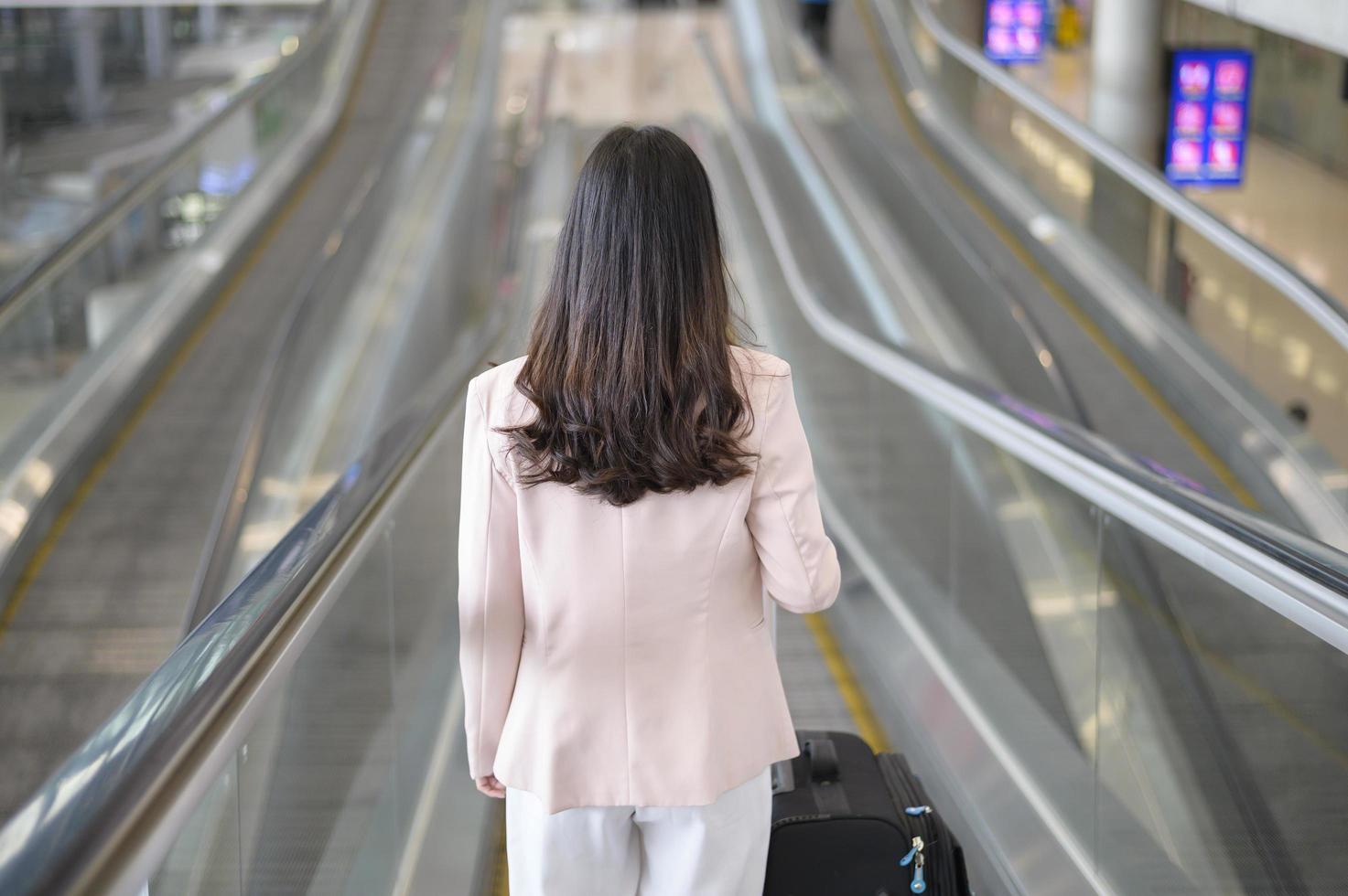 una donna d'affari indossa una maschera protettiva nell'aeroporto internazionale, viaggia sotto la pandemia covid-19, viaggi di sicurezza, protocollo di allontanamento sociale, nuovo concetto di viaggio normale foto