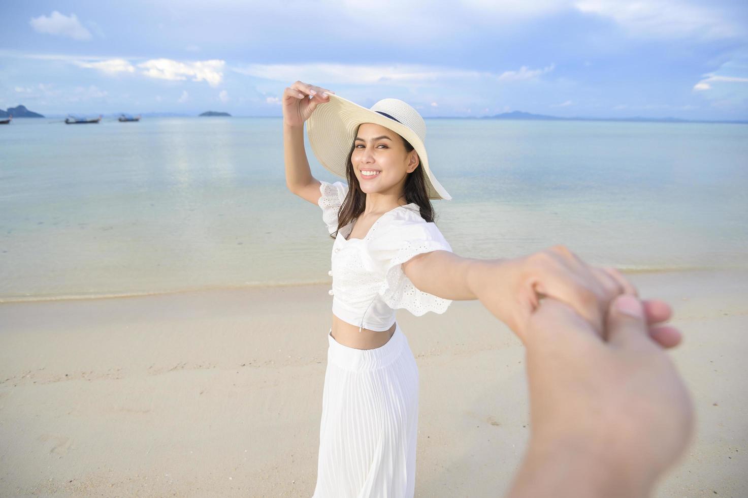 una bella donna felice in abito bianco che si gode e si rilassa sul concetto di spiaggia, estate e vacanze foto
