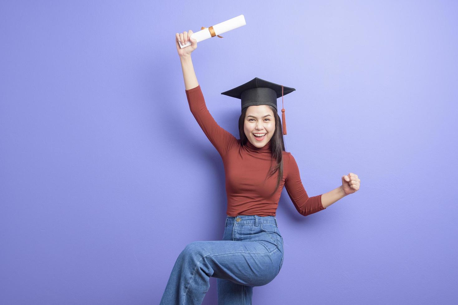 ritratto di giovane studentessa universitaria con cappuccio di laurea su sfondo viola foto