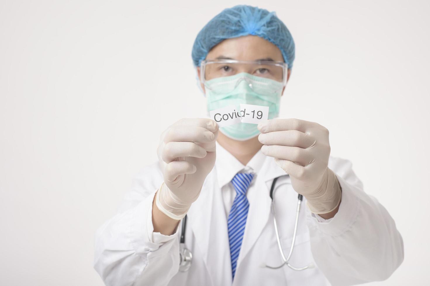 il medico tiene la carta covid-19 su sfondo bianco foto