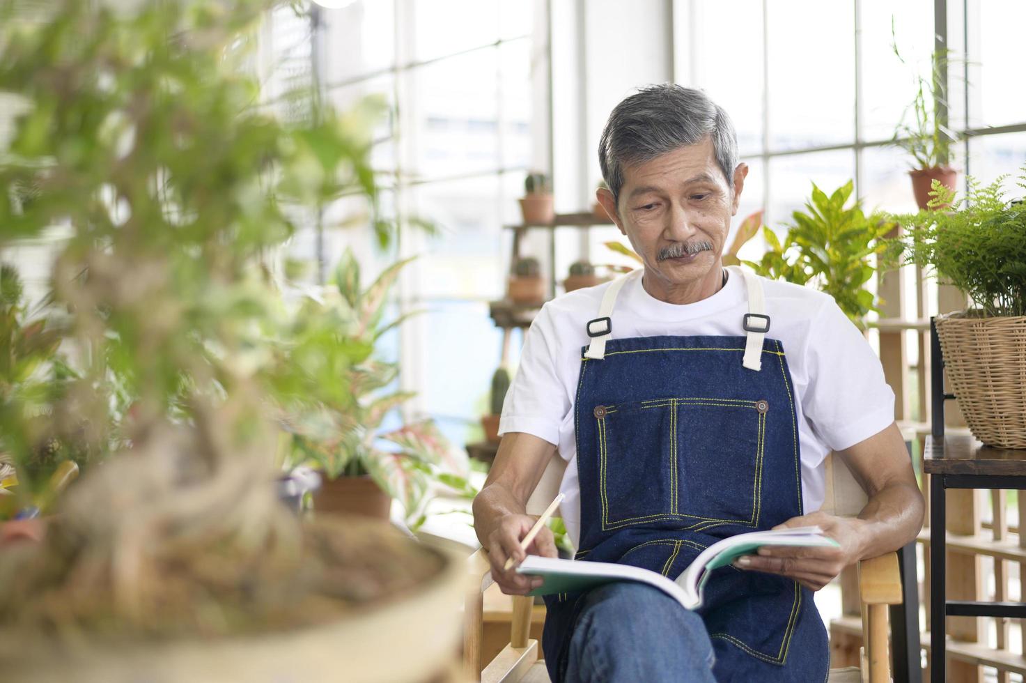 felice anziano asiatico pensionato che legge e si gode l'attività di svago in giardino a casa. foto