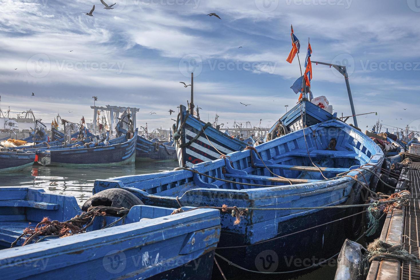 barche da pesca in legno blu ancorate al porto turistico contro il cielo nuvoloso foto