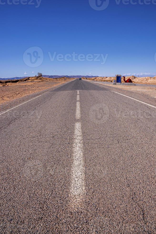 strada asfaltata diritta con i contrassegni attraverso il deserto contro il cielo foto