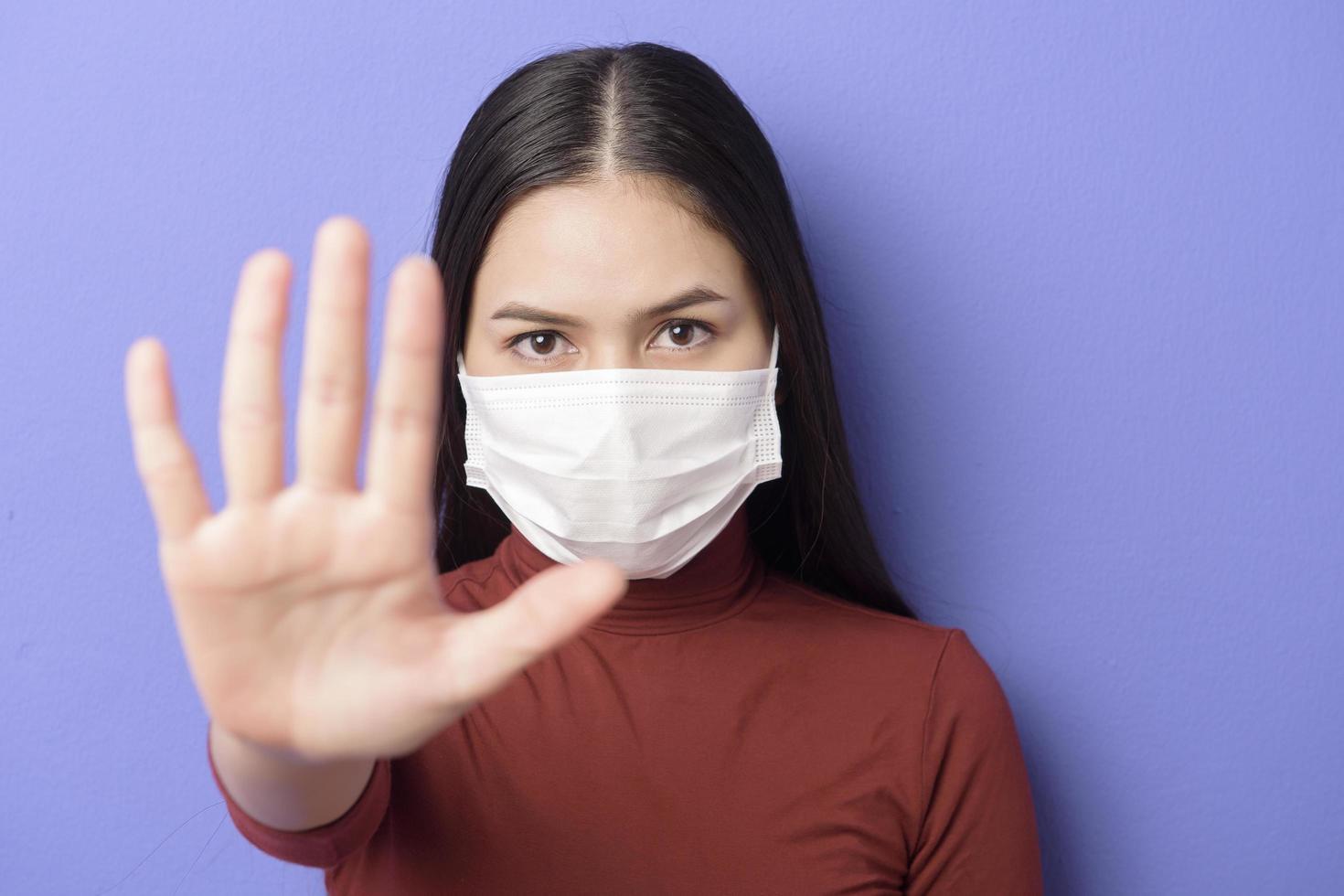 il ritratto di una giovane donna indossa una maschera facciale su sfondo viola foto