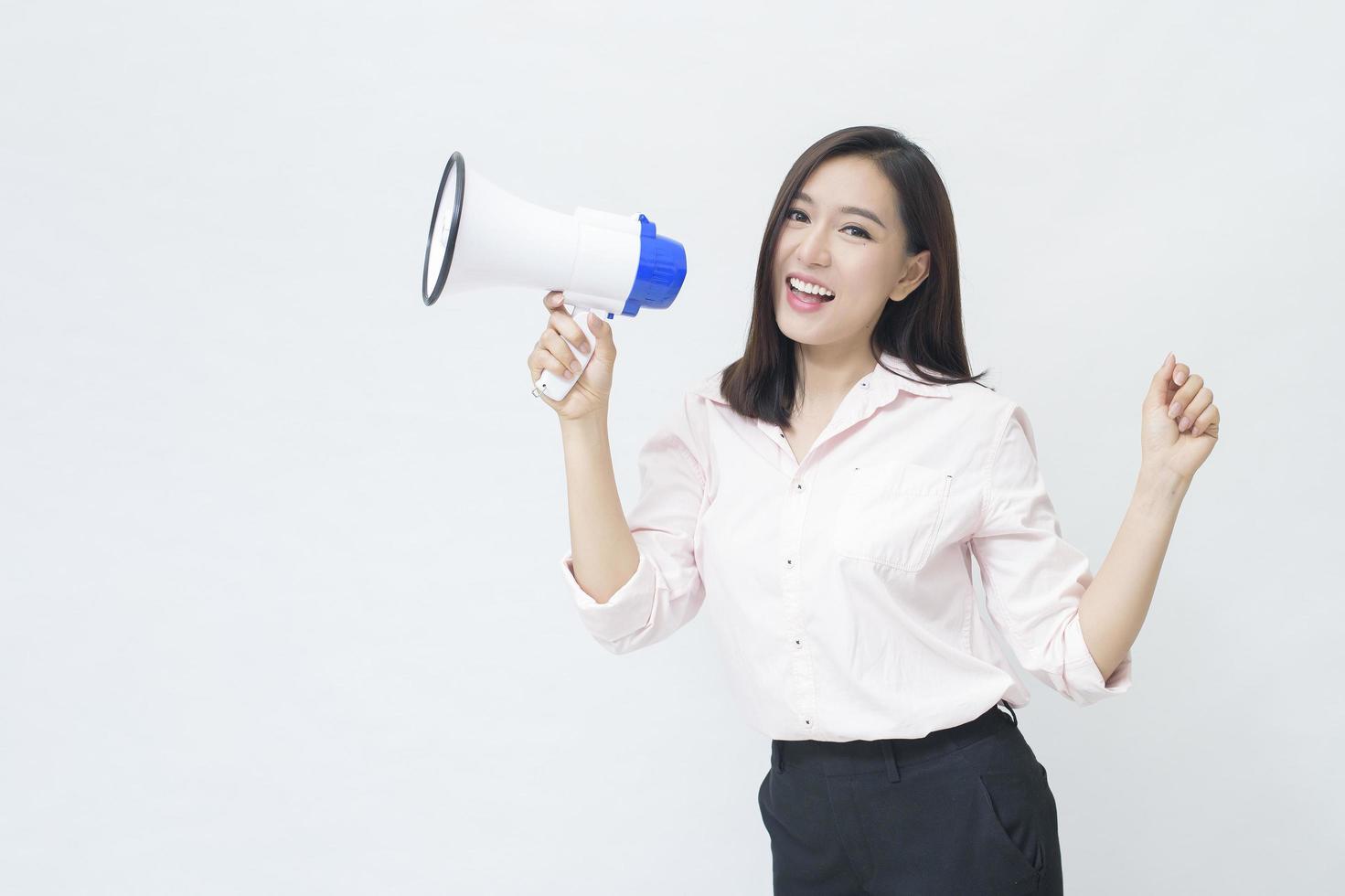 una giovane bella donna asiatica sta annunciando dal megafono su sfondo bianco foto