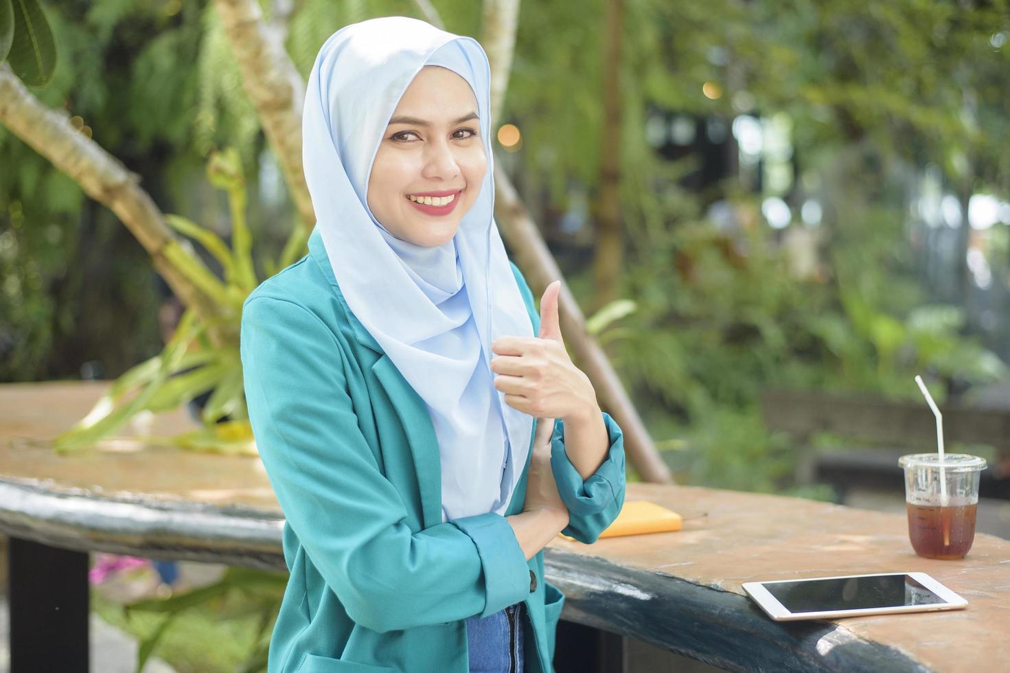 la donna musulmana con l'hijab sta lavorando con il computer portatile nella caffetteria foto