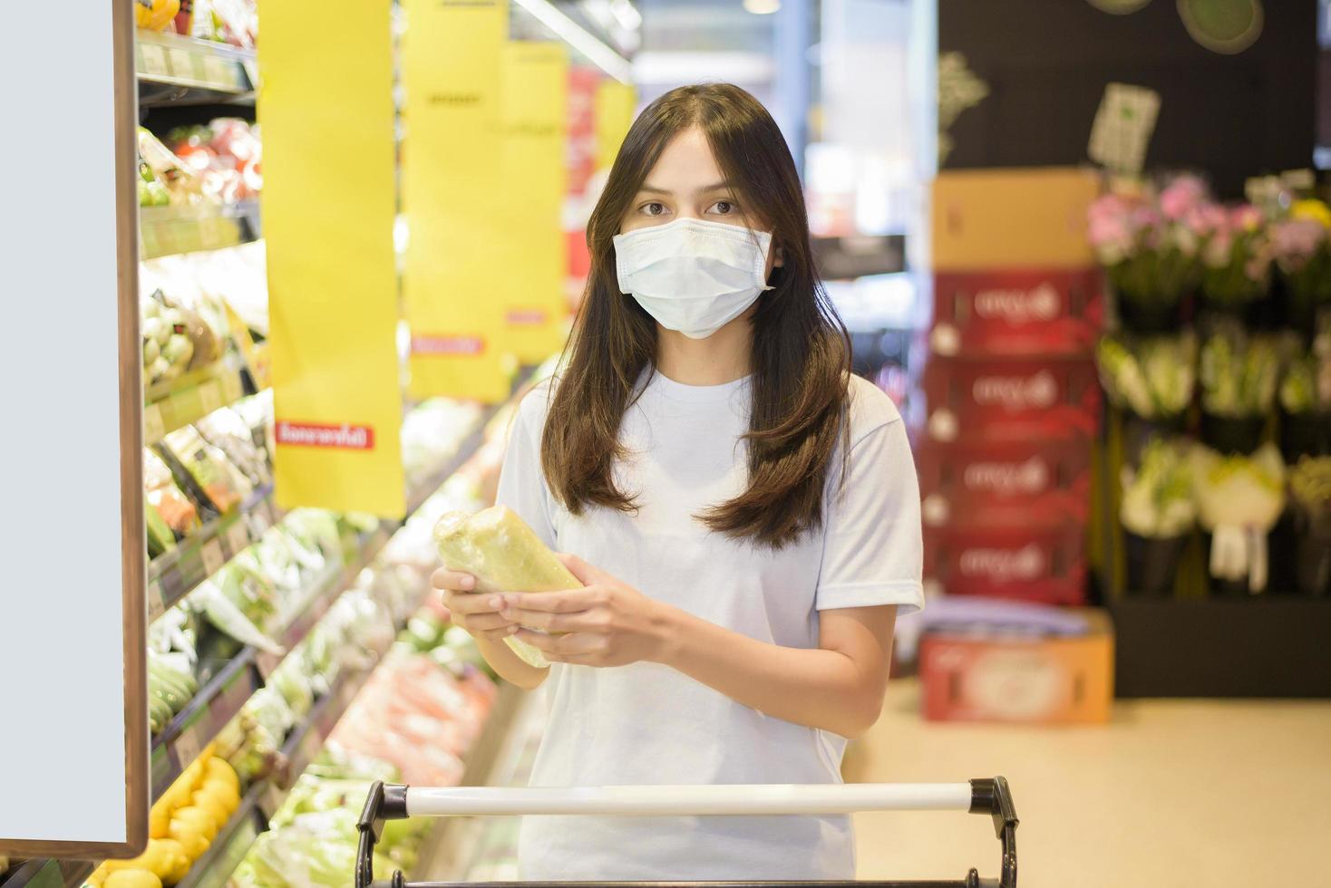 la donna sta facendo la spesa al supermercato con la maschera foto