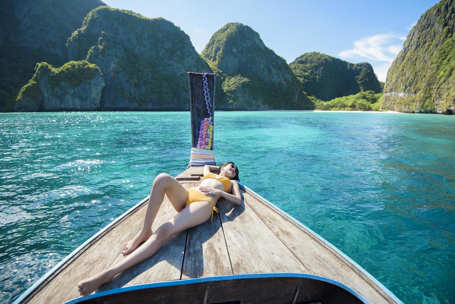 Vista della donna in costume da bagno godendo sulla tradizionale barca tailandese a coda lunga sulla bellissima montagna e sull'oceano, isole phi phi, tailandia foto