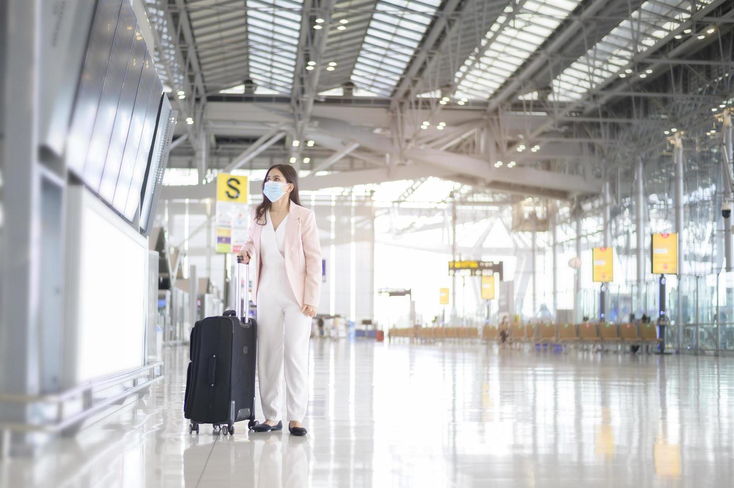 una donna d'affari indossa una maschera protettiva nell'aeroporto internazionale, viaggia sotto la pandemia covid-19, viaggi di sicurezza, protocollo di allontanamento sociale, nuovo concetto di viaggio normale foto