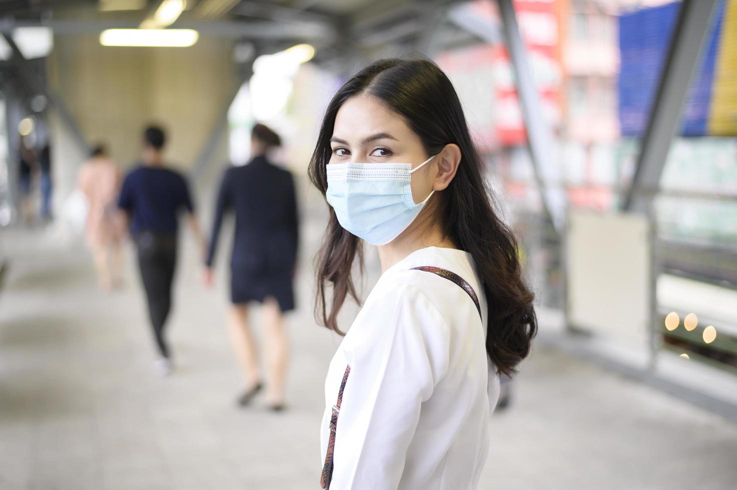 una giovane donna indossa una maschera per il viso nella città di strada. foto