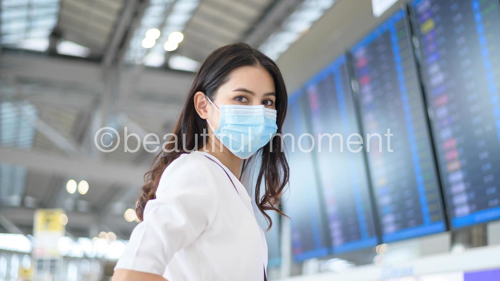 una donna viaggiatrice indossa una maschera protettiva nell'aeroporto internazionale, viaggia sotto la pandemia covid-19, viaggi di sicurezza, protocollo di allontanamento sociale, nuovo concetto di viaggio normale foto