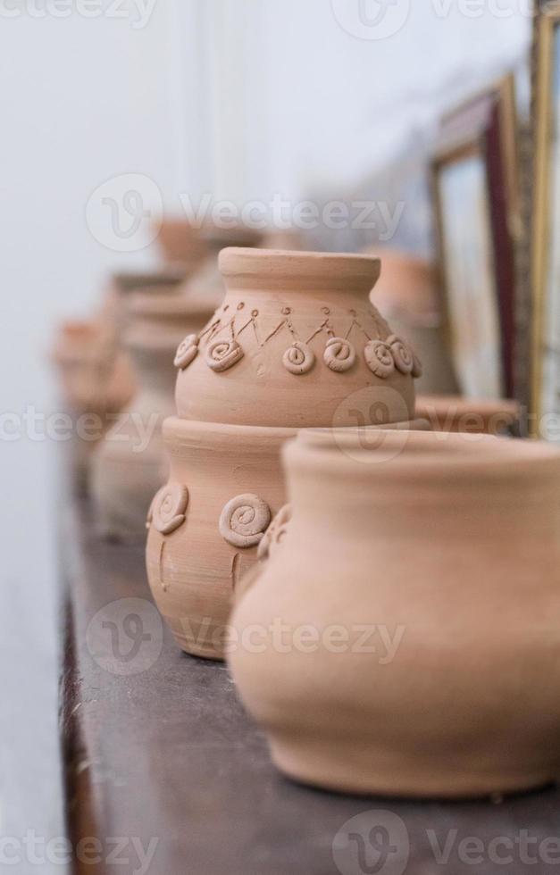 fila di vasi di terracotta sullo scaffale, sfondo sfocato. artigianato per bambini foto