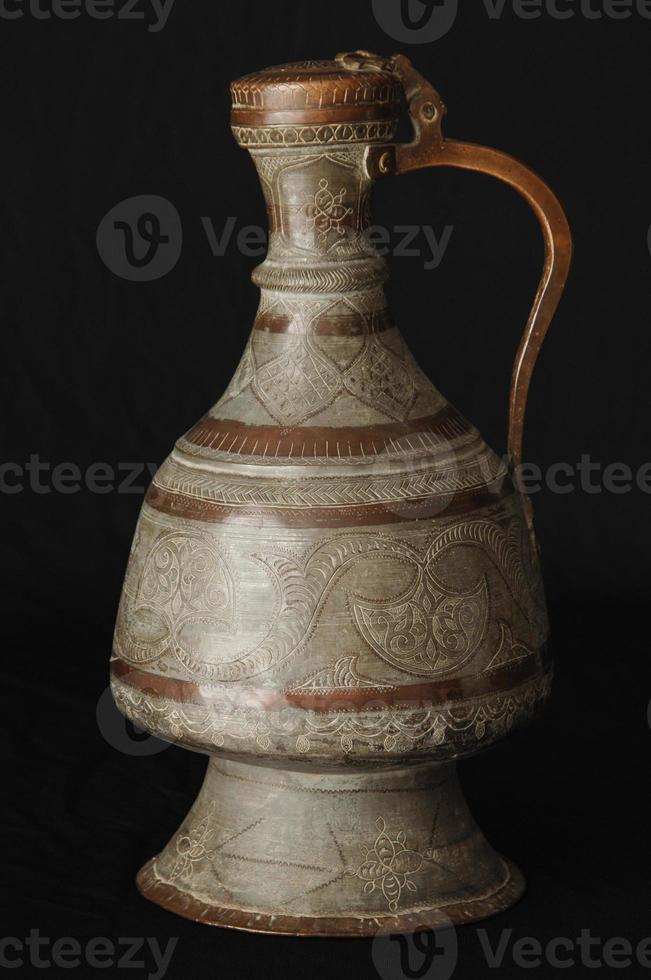 antica brocca di metallo orientale su sfondo scuro. stoviglie in bronzo antico foto