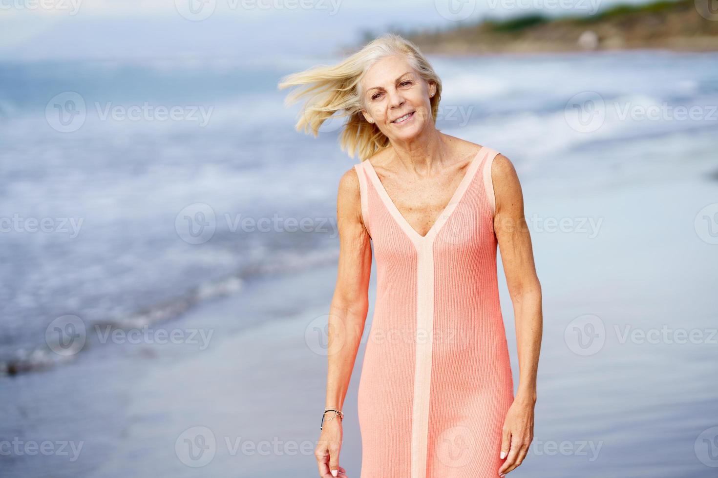 donna anziana che si gode la pensione in un rifugio sul mare. donna anziana sulla riva di una spiaggia. foto