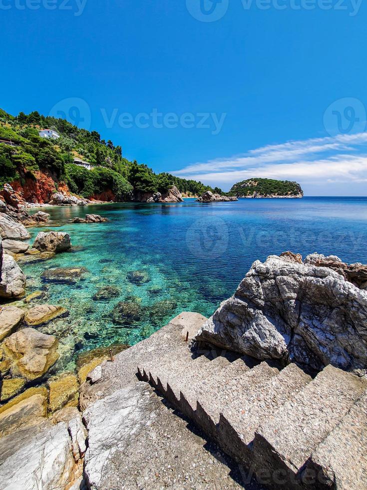 vista incontaminata della baia di un'isola greca con gradini in cemento che conducono all'acqua. foto