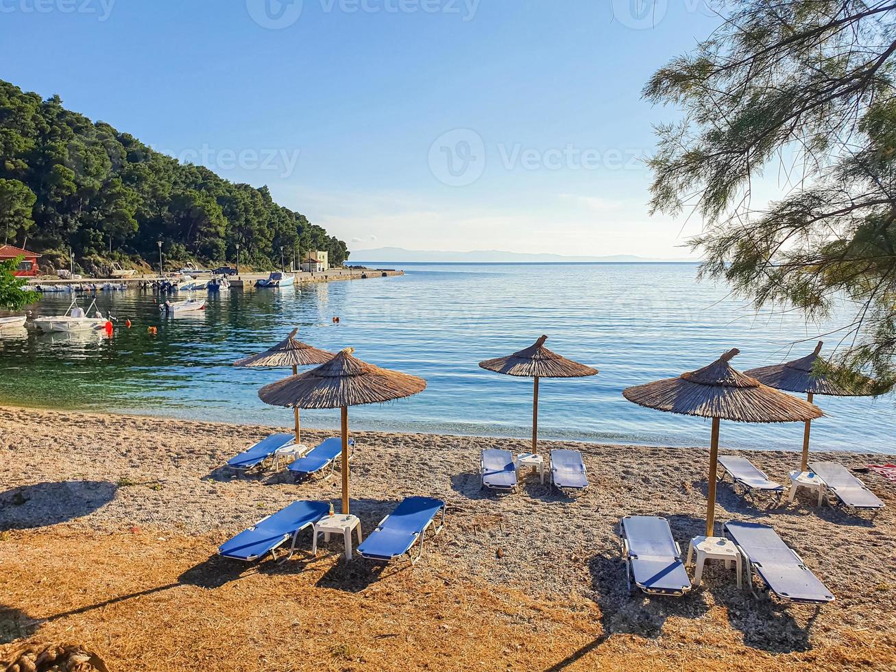 vista incontaminata della baia di un'isola greca con lettini e ombrelloni vuoti. foto