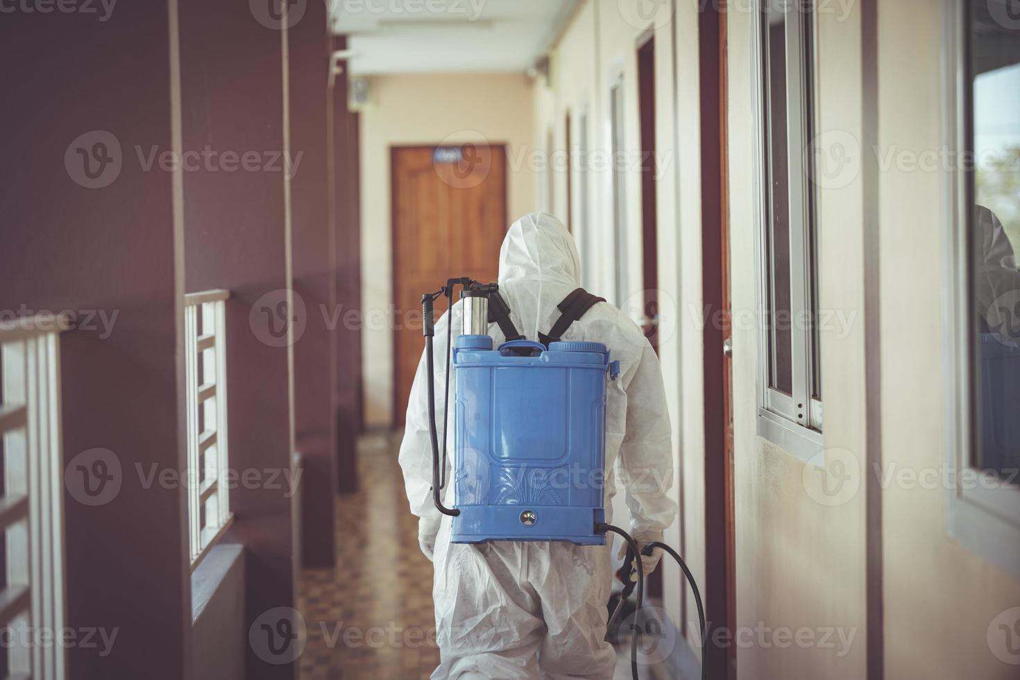 dietro il personale medico che indossa l'uniforme dpi che spruzza disinfettante contro la diffusione del virus. foto