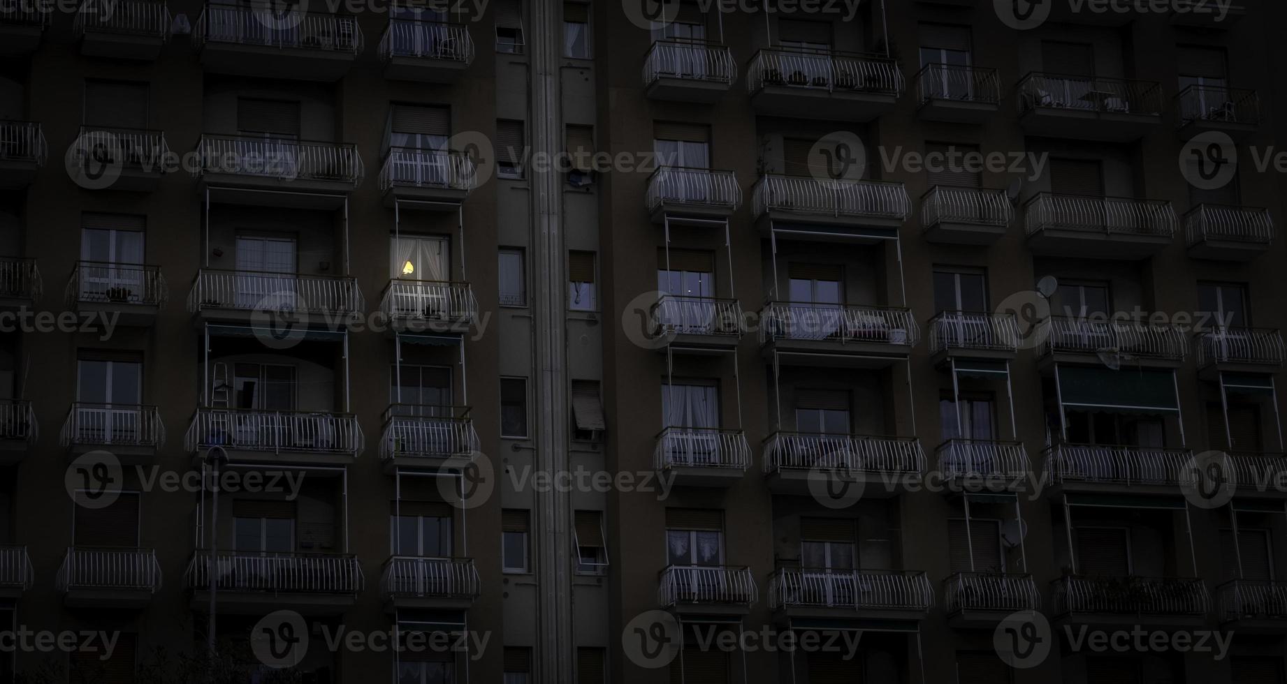 una finestra illuminata da luce elettrica svetta su una facciata di un edificio della liguria occidentale foto