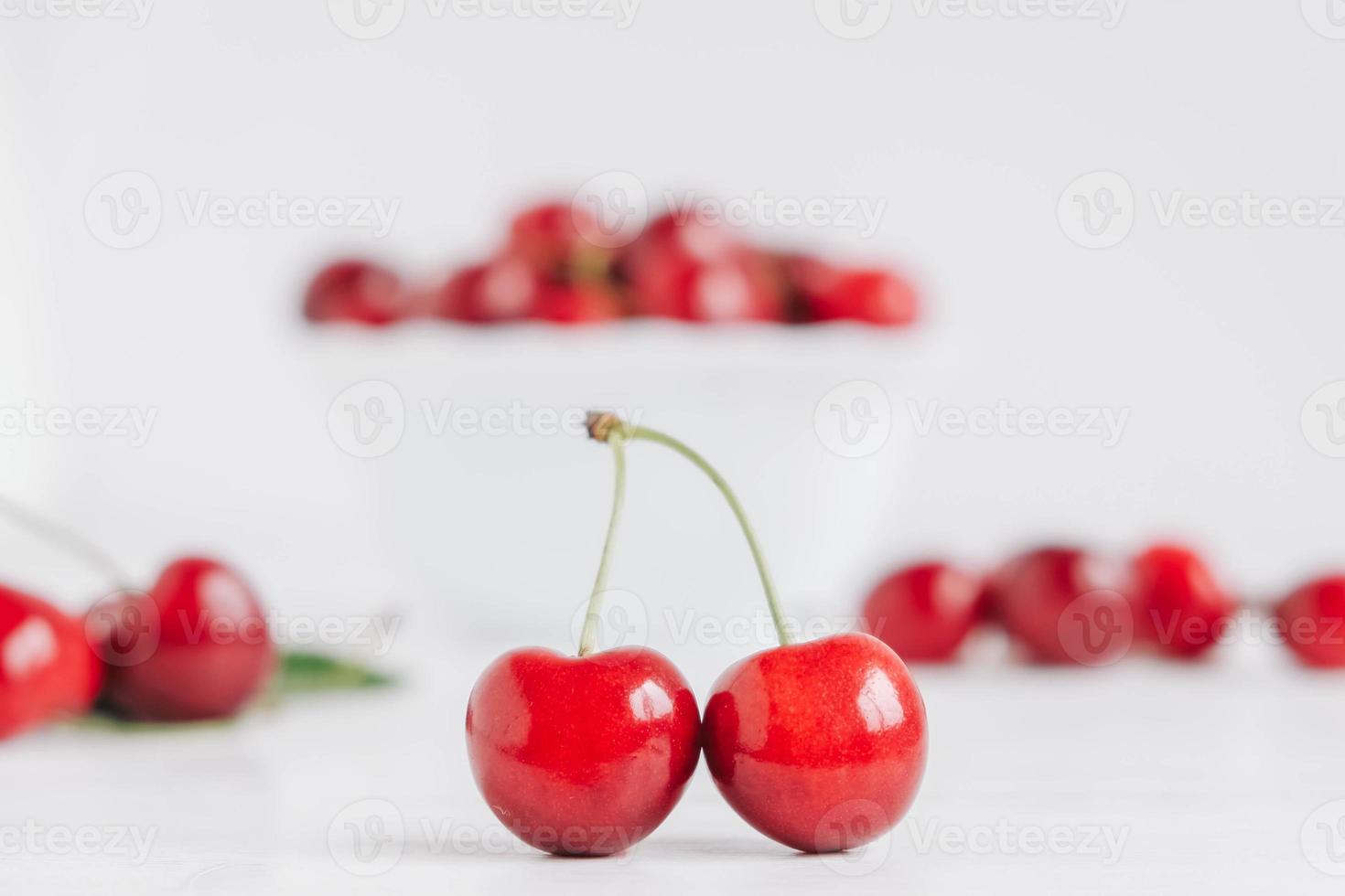 ciliegie rosse succose fresche in un piatto bianco su fondo di legno bianco foto