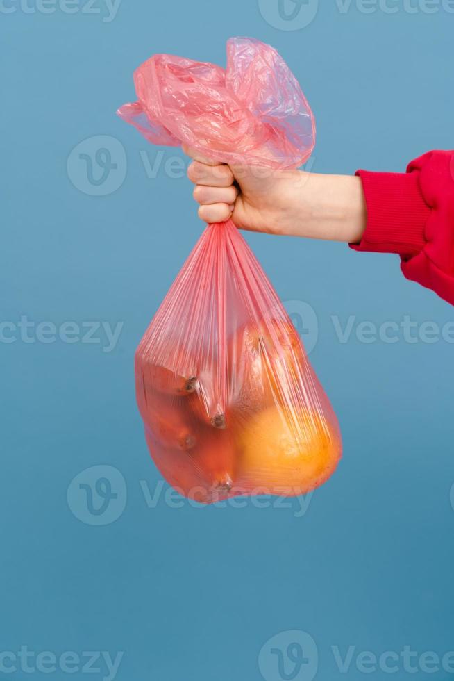 giovane donna che indossa un maglione rosso che tiene un sacchetto di plastica per la spazzatura foto