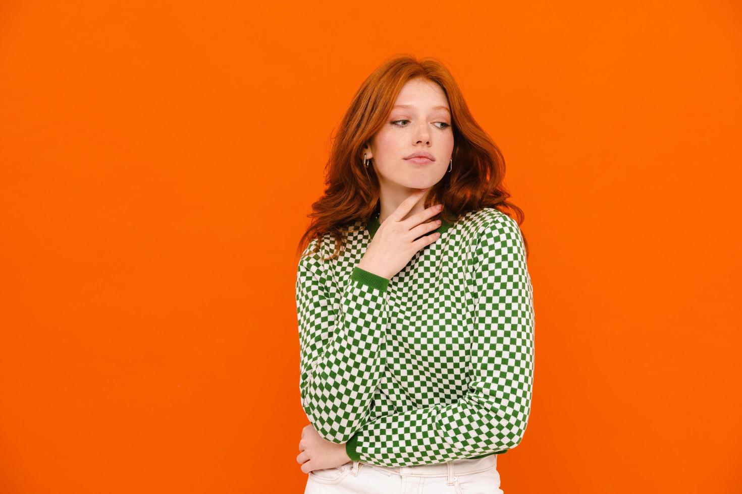 giovane donna zenzero in maglione plaid che guarda da parte foto