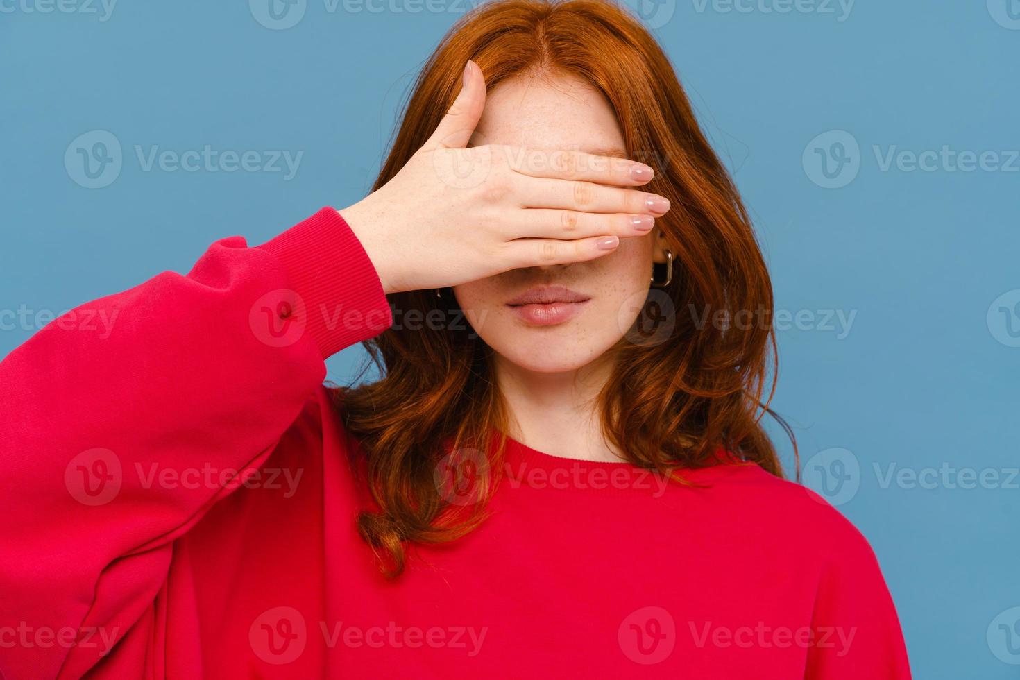 giovane donna zenzero che indossa un maglione rosso che copre gli occhi foto