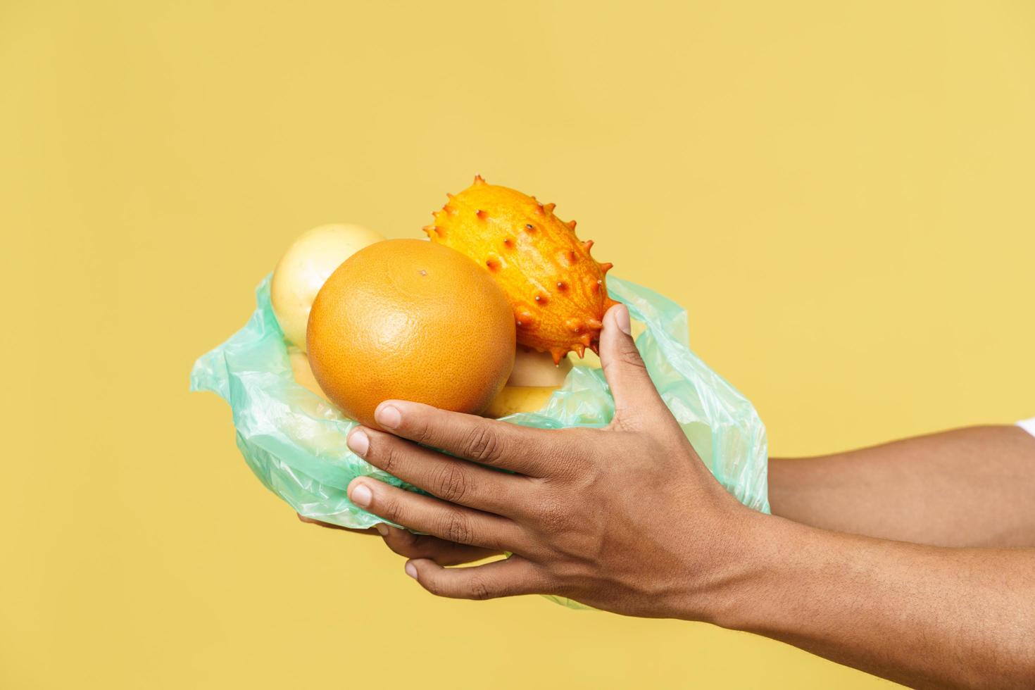 mani maschili che tengono la frutta nel sacchetto della spazzatura di plastica foto