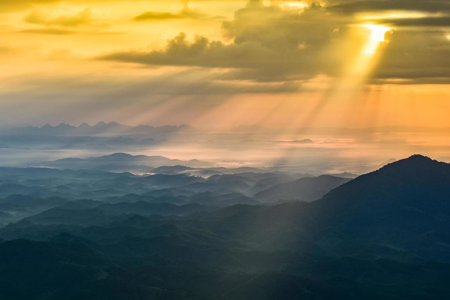 meraviglioso paesaggio alba al mattino nuovo giorno sulla collina di montagna con raggi di sole che brillano sul cielo nuvoloso foto