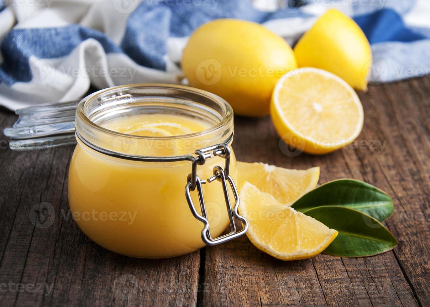 lemon curd in vasetto di vetro con limoni freschi foto