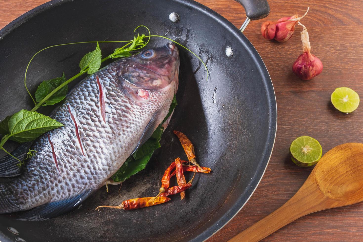 pesce fresco in padella e spezie per cucinare foto