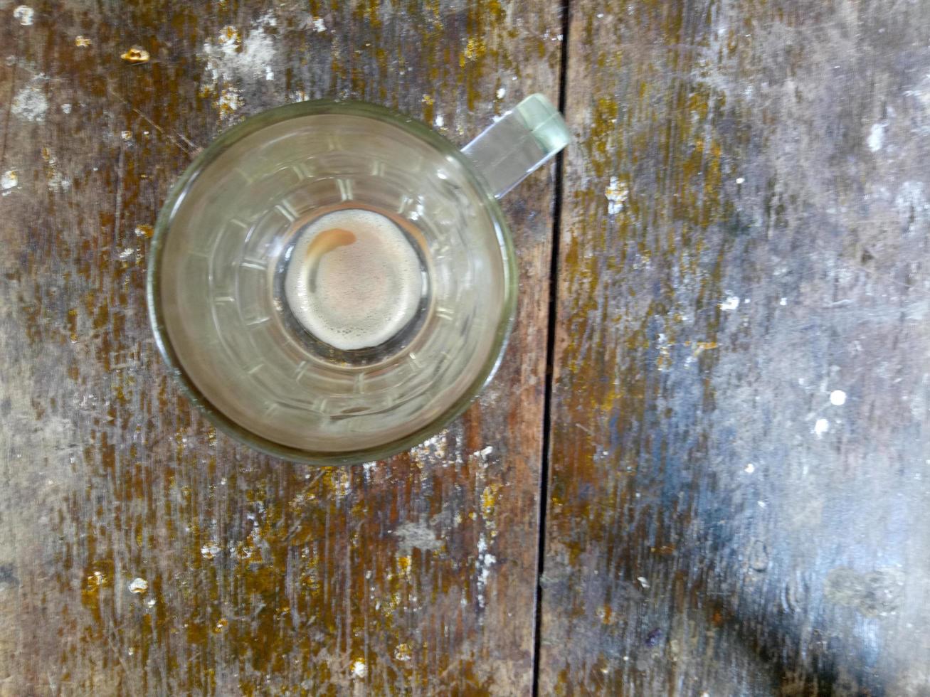 bicchiere sporco di caffè avanzato su uno sfondo di legno marrone foto