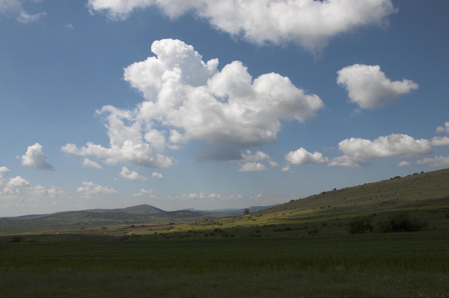 bellissimo paesaggio con colline, campi verdi e cielo azzurro con nuvole bianche. soria, spagna foto